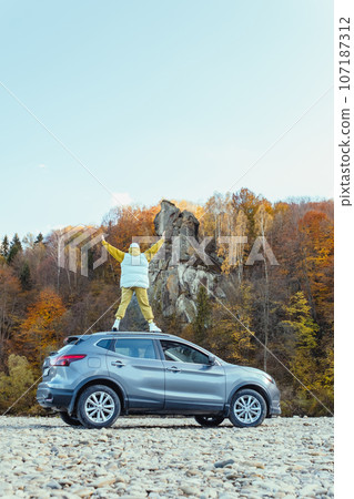 happy woman at car roof enjoying the view of autumn river in carpathian mountains happy woman at car roof enjoying the view of autumn river in carpathian mountains 107187312