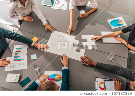 Businessmen working together to build a puzzle as teamwork, partnership and integration concept 107187559