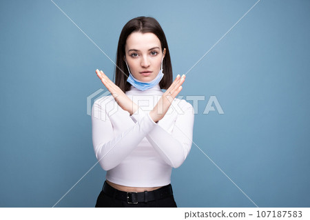 A young girl put on a medical mask incorrectly. The woman shows an error while wearing a mask 107187583