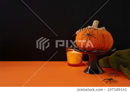Autumn handmade textile decoration on orange table. Cozy fabric pumpkin. Halloween decor. 107189141