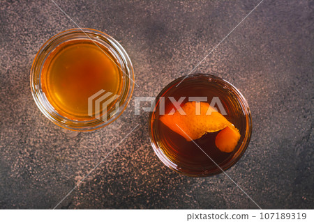 Close up of hard alcoholic brown butter cocktail with orange zest in a glass top view 107189319