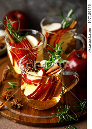 Christmas mulled apple cider with cinnamon, anise and rosemary. Traditional hot drink or beverage, festive Xmas or New Year winter cocktail 107189536