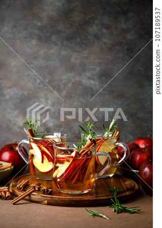 Christmas mulled apple cider with cinnamon, anise and rosemary. Traditional hot drink or beverage, festive Xmas or New Year winter cocktail 107189537