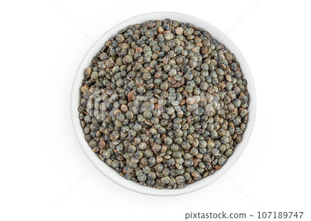 raw french green lentils in ceramic bowl isolated on white background. Top view. Flat lay 107189747