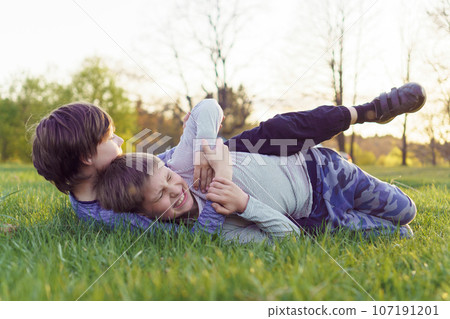 Boy trying to grab and immobilize comrade who wrinkled face attempting to win, friends fighting and playing on meadow. Boy trying to grab and immobilize comrade who wrinkled face attempting to win, friends fighting and playing on meadow. 107191201