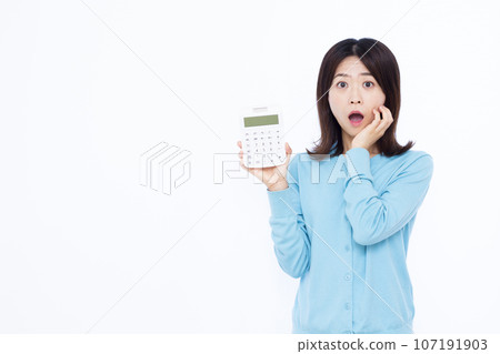 一位 30 多歲的驚訝女性在白色背景前拿著計算器 一位 30 多歲的驚訝女性在白色背景前拿著計算器 107191903