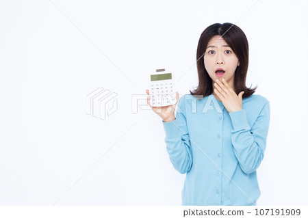 一位 30 多歲的驚訝女性在白色背景前拿著計算器 一位 30 多歲的驚訝女性在白色背景前拿著計算器 107191909