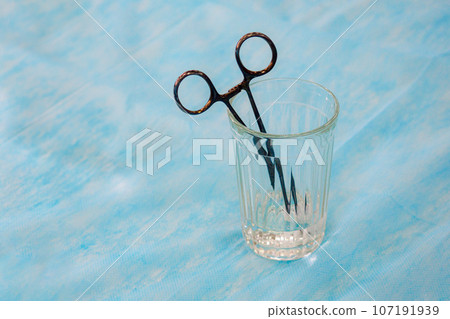 Medical clamp is in cut glass cup. Medicine shortage concept. Outdated treatment methods. Background Medical clamp is in cut glass cup. Medicine shortage concept. Outdated treatment methods. Background 107191939