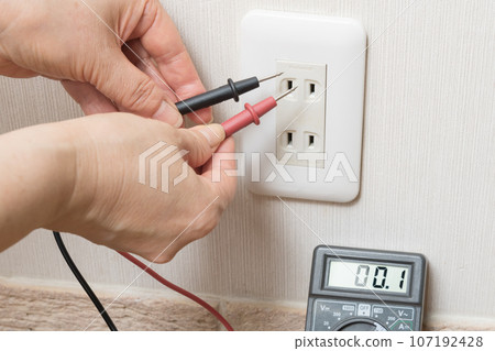 [Housewife measuring outlet voltage with a tester] 107192428