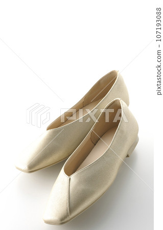 Low-soled gold women's shoes and pumps photographed against a white background 107193088
