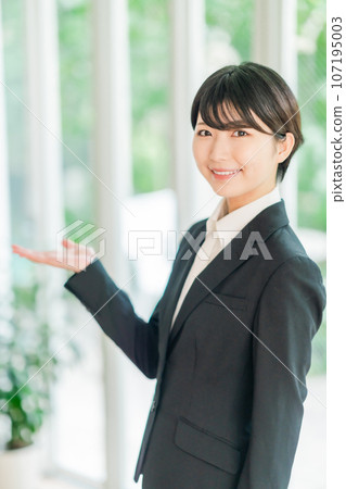 A young woman in a suit posing in a refreshing bright room 107195003