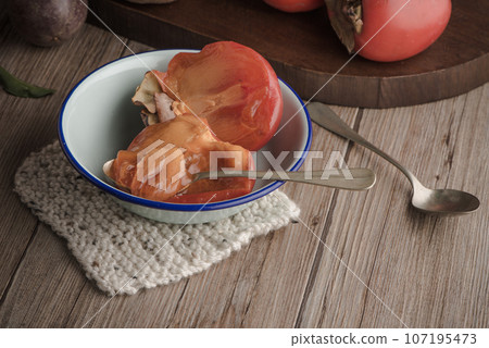 Persimmon fruit on rustic table 107195473