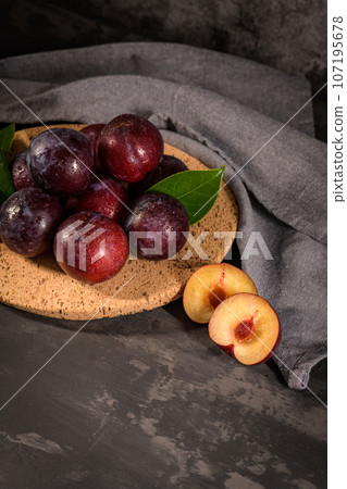 Red plums in a cork plate Red plums in a cork plate 107195678