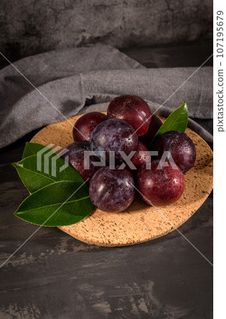 Red plums in a cork plate 107195679
