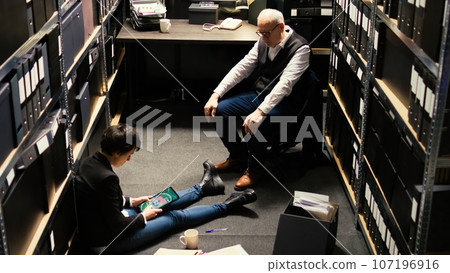 Agents team review statements and surveillance footage, using classified file records. Private detectives waiting to receive forensic evidence authenticity report, build suspect profile. Agents team review statements and surveillance footage, using classified file records. Private detectives waiting to receive forensic evidence authenticity report, build suspect profile. 107196916