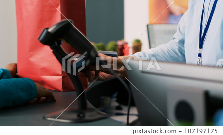 African american woman paying for stylish clothes with credit card using payment terminal during shopping session in modern boutique. Customer buying formal wear in clothing store. Fashion concept 107197175