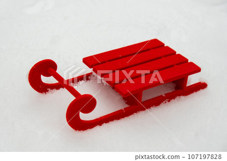 Small Red sled on snow background in beautiful winter day. Copy space for text. Mock up for product greeting card or wallpaper. Christmas 107197828