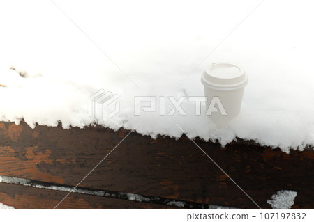 Hot warming drink in Eco paper cup. Mock up Cardboard coffee or tea Cup in the snow in winter day. Copy space zero waste recycle cup white snow-covered field Hot warming drink in Eco paper cup. Mock up Cardboard coffee or tea Cup in the snow in winter day. Copy space zero waste recycle cup white snow-covered field 107197832