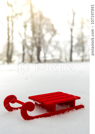 Small Red sled on snow background in beautiful winter day. Copy space for text. Mock up for product greeting card or wallpaper. Christmas 107197891