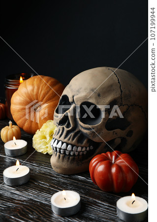 Skull, pumpkins and candles on wooden table on black background Skull, pumpkins and candles on wooden table on black background 107199944
