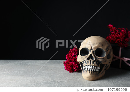 Skull and flowers on black background, space for text 107199996