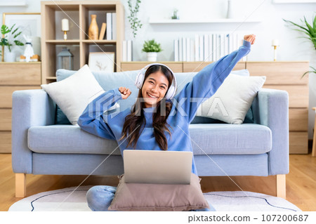 Young asian woman in good spirits working on laptop at home Young asian woman in good spirits working on laptop at home 107200687