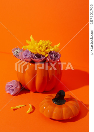 Pumpkin vase with flowers on orange background Pumpkin vase with flowers on orange background 107201706