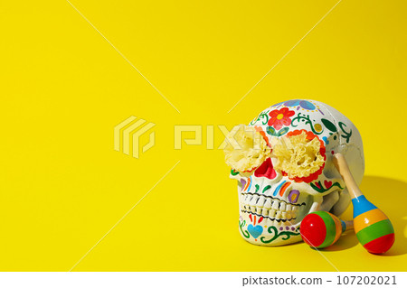 Mexican skull, flowers and maracas on yellow background, space for text 107202021