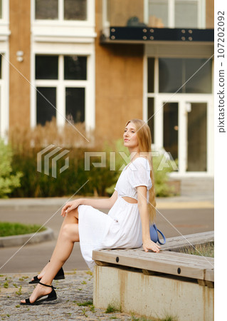 Cute woman resting on a bench in residential area 107202092