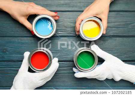Jars with paints and hands on wooden background, top view 107202185