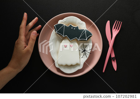Pink cutlery with cookies on a black background Pink cutlery with cookies on a black background 107202981