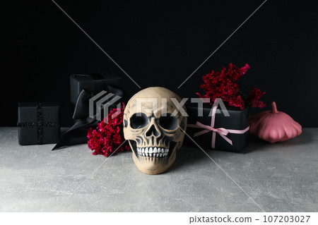 Skull, gift boxes and flowers on black background, space for text 107203027