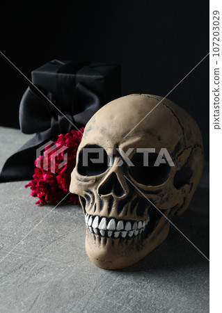 Skull, gift box and flower on black background, close up 107203029