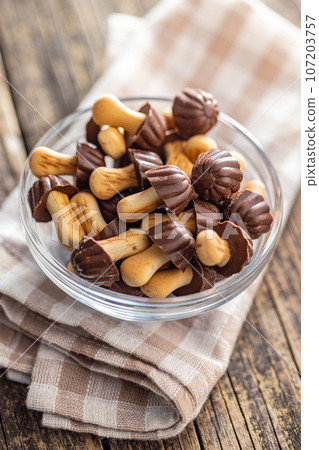 Candy in the shape of a mushroom. Chocolate mushrooms in bowl on wooden table. Candy in the shape of a mushroom. Chocolate mushrooms in bowl on wooden table. 107203757