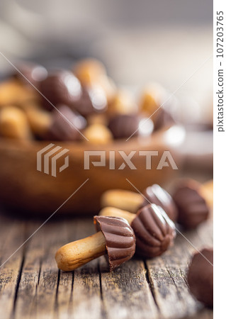 Candy in the shape of a mushroom. Chocolate mushrooms on wooden table. Candy in the shape of a mushroom. Chocolate mushrooms on wooden table. 107203765