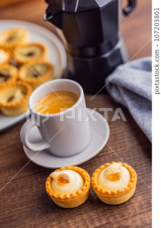 Sweet tarlets. Tasty mini tarts. Mini pie with cream and coffee cup  on kitchen table. 107203801