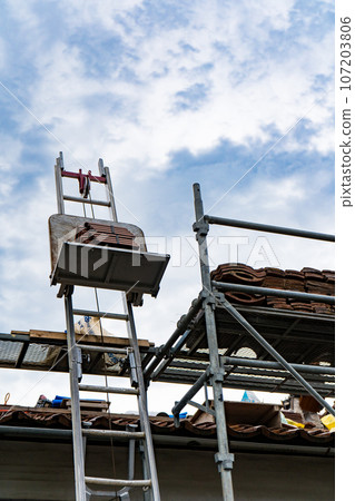 Scaffolding installed to replace roof tiles of an old detached house | Roof renovation image | Tile renovation image Scaffolding installed to replace roof tiles of an old detached house | Roof renovation image | Tile renovation image 107203806