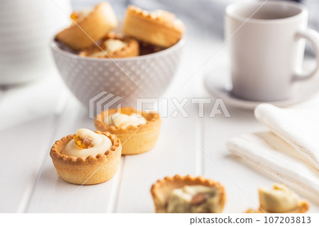 Sweet tarlets. Tasty mini tarts. Mini pie with cream on kitchen table. 107203813