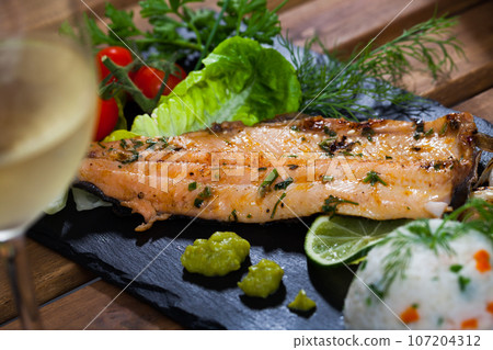 Baked trout fillet with rice, vegetables and white wine 107204312