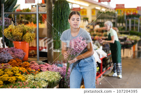 Smiling girl buying bouquet of colorful fresh flowers at market 107204395