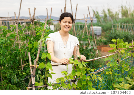 Female farmer enjoying while working in vegetable garden. Female farmer enjoying while working in vegetable garden. 107204463