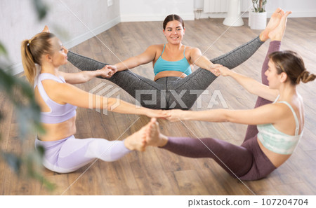 Young woman practicing 3 people group position in yoga studio 107204704