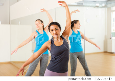 Hispanic woman practicing ballet dance moves in choreographic studio 107204812