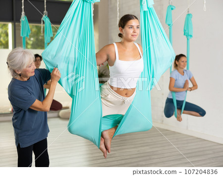 Aerial yoga trainer teaching women in gym Aerial yoga trainer teaching women in gym 107204836