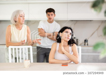 Sad woman dont speaking after discord with mother and husband standing behind 107204949