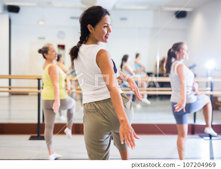 Asian girl dancing modern dance in studio with other dancers Asian girl dancing modern dance in studio with other dancers 107204969