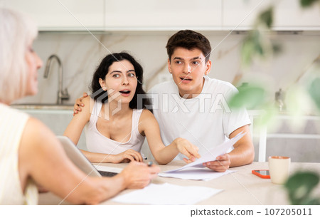 Married couple of clients listen attentively and intently to elderly woman of seller 107205011