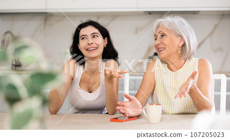 Young woman and elderly woman drinking tea in kitchen 107205023