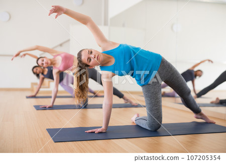 Girl doing Vasisthasana during group yoga workout Girl doing Vasisthasana during group yoga workout 107205354