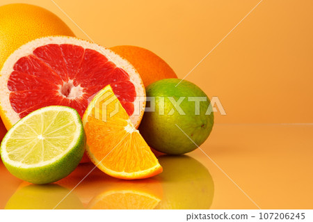 Cut pieces of citrus fruits on orange background 107206245
